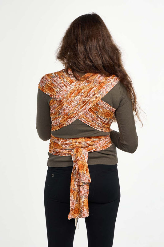 Zdjęcie mamy widzianej z tyłu noszącej dziecko w chuście elastycznej Tula Sunflower