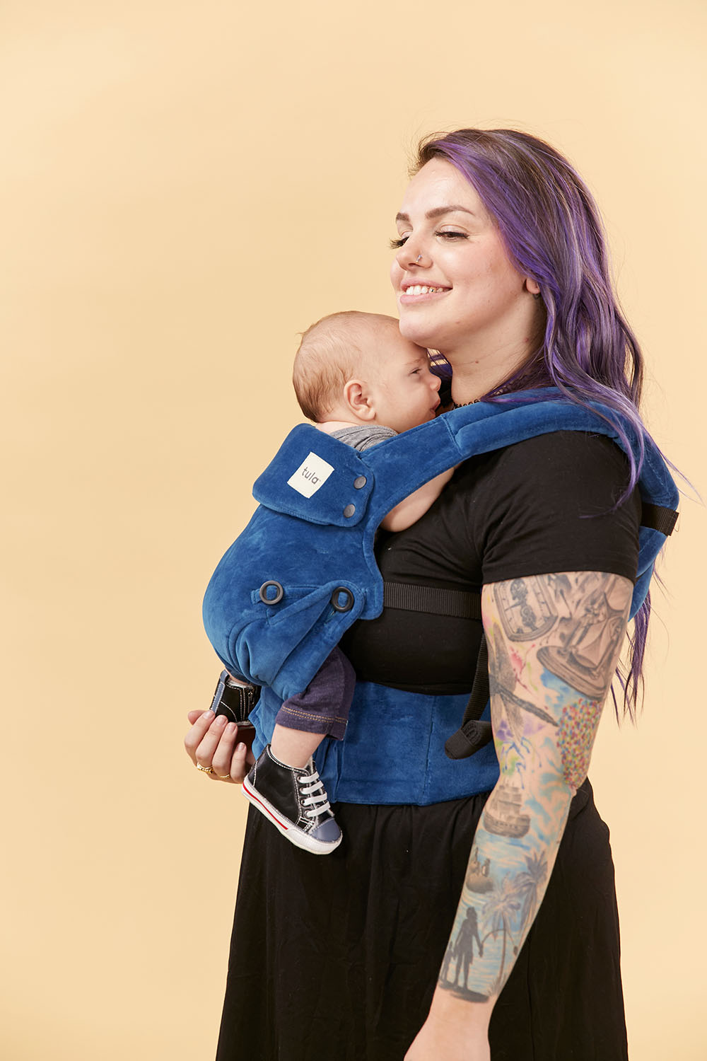 Uśmiechnięta mama tuli dziecko w nosidełku Tula Explore Velour