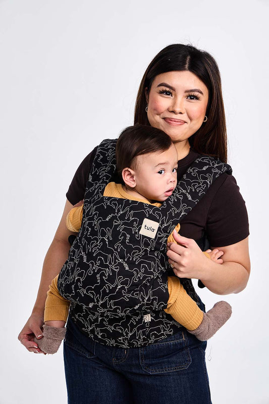 Szczęśliwa mama z dzieckiem w nosidełku Tula Explore Dakota z haftem sylwetek koni