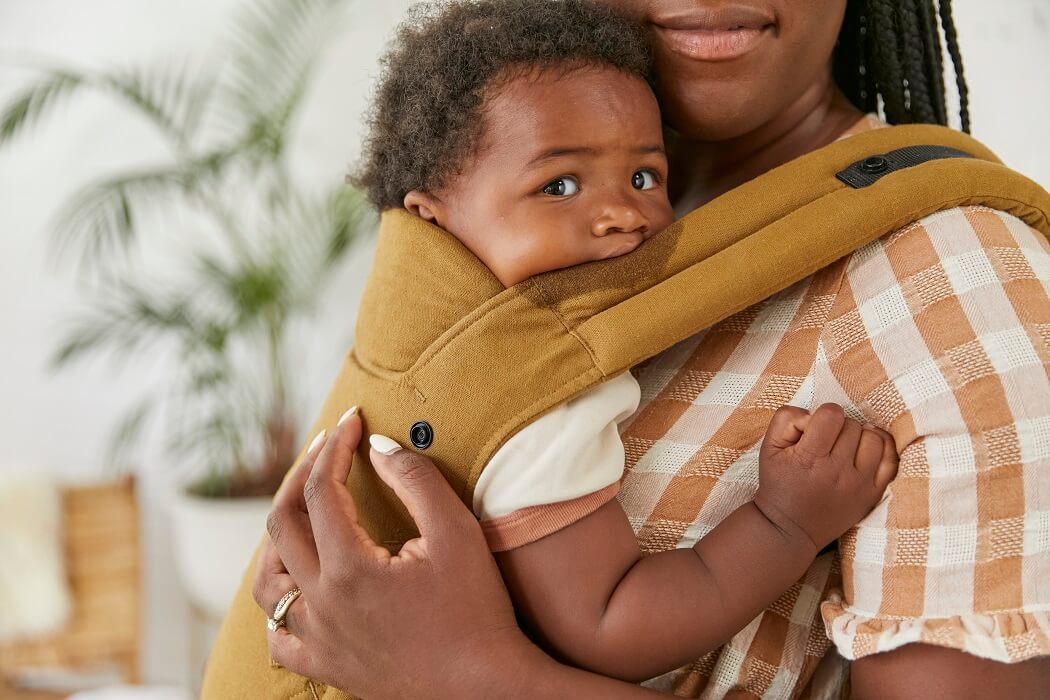 Uśmiechnięta mama nosi w ergonomicznym nosidełku Tula Explore Hemp z konopi.