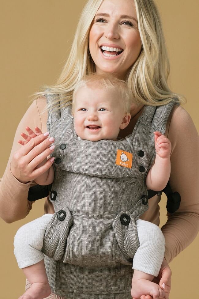 Mama nosi niemowlę w nosidełku Tula Explore w pozycji przodem do świata