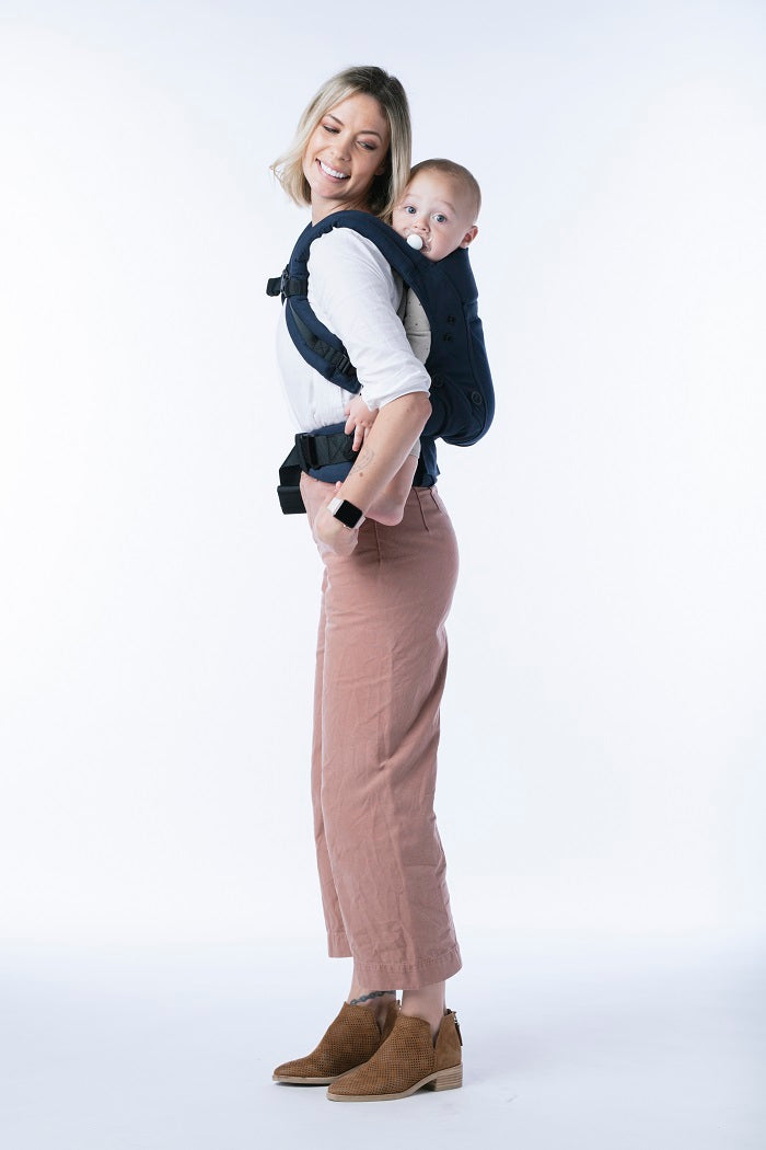 Mama nosi niemowlę w pozycji na plecach w nosidełku Tula Explore 