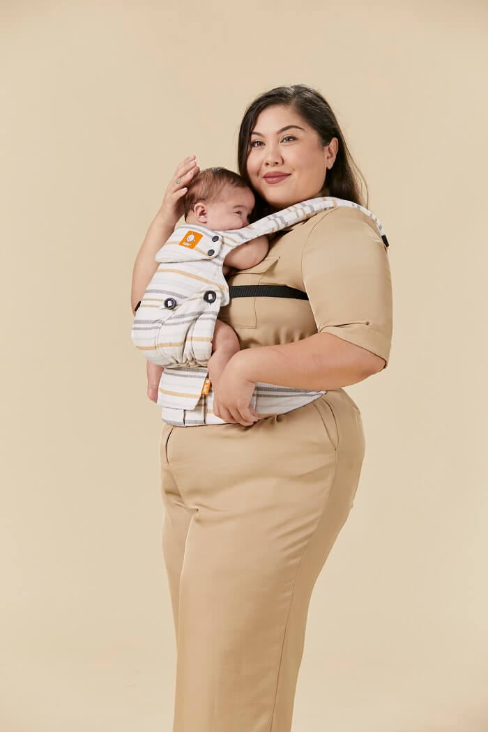 Mama nosi dziecko w ergonomiczneym nosidełku dla niemowlaka.
