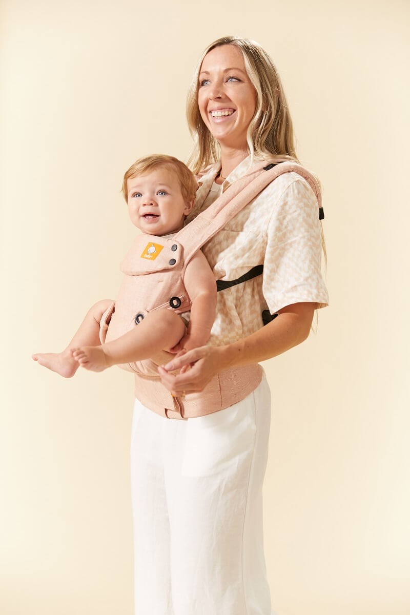 Opiekun noszący w ergonomicznym nosidełku Tula dla noworodków w pozycji przodem do rodzica