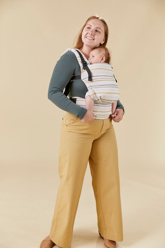 Mama nosi dziecko w ergonomicznym nosidełku od urodzenia uszytym z mieszanki konopi i bawełny.