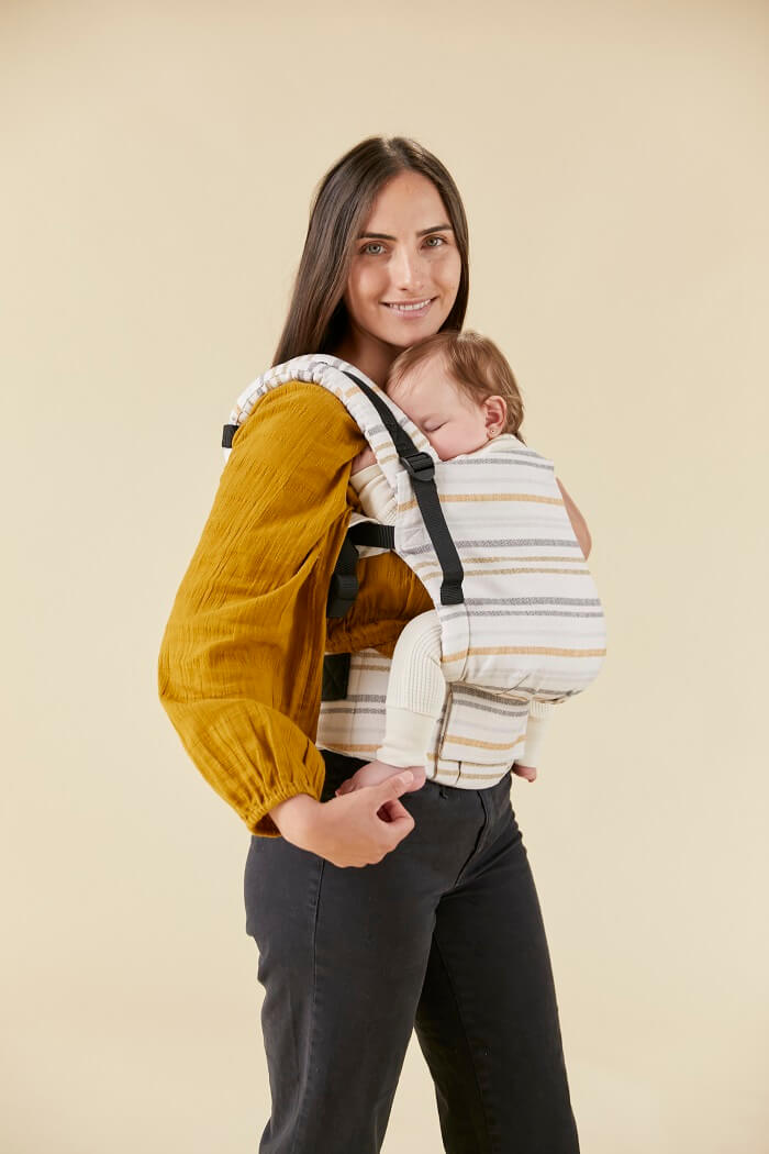Mama nosi dziecko w ergonomicznym nosidełku od urodzenia.