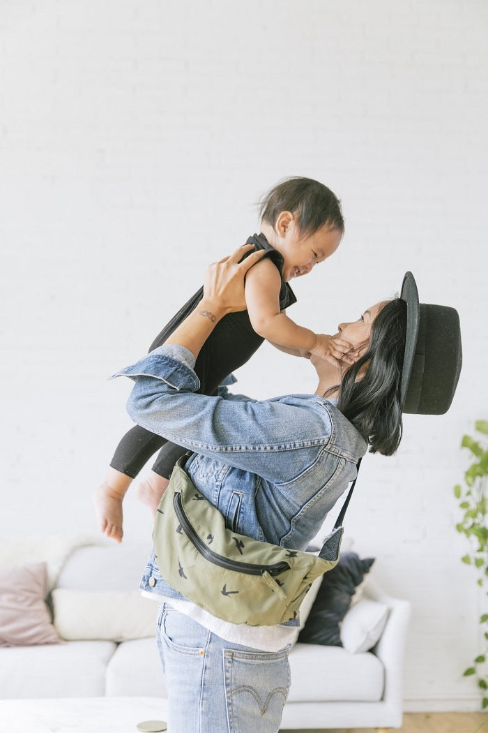 Mama z nerką z nosidełkiem Tula Lite na ramieniu bawi się z dzieckiem