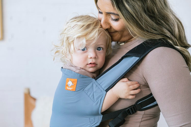Mama nosi dziecko w pozycji przodem do rodzica w nosidełku Tula Lite Slate. 