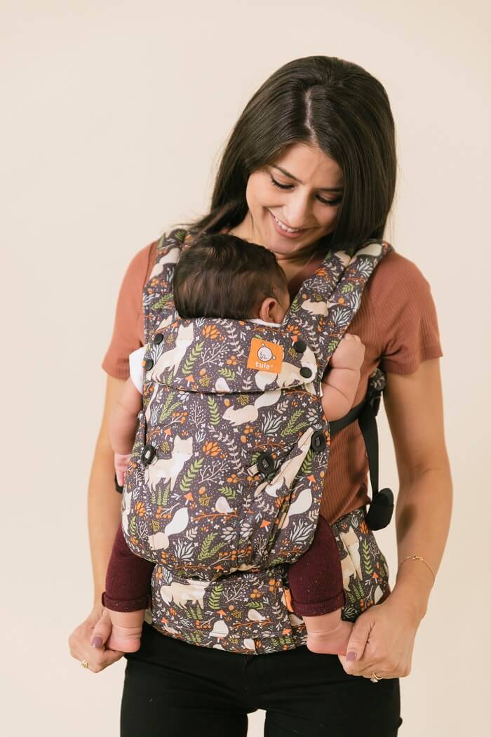 Mama nosi dziecko w ergonomicznej pozycji serce do serca w nosidełku Tula Explore Fox Tail