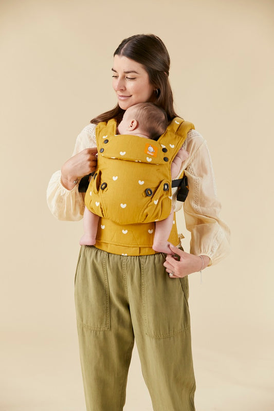Mama nosi śpiące dziecko w ergonomicznej pozycji w nosidełku Tula Explore Play