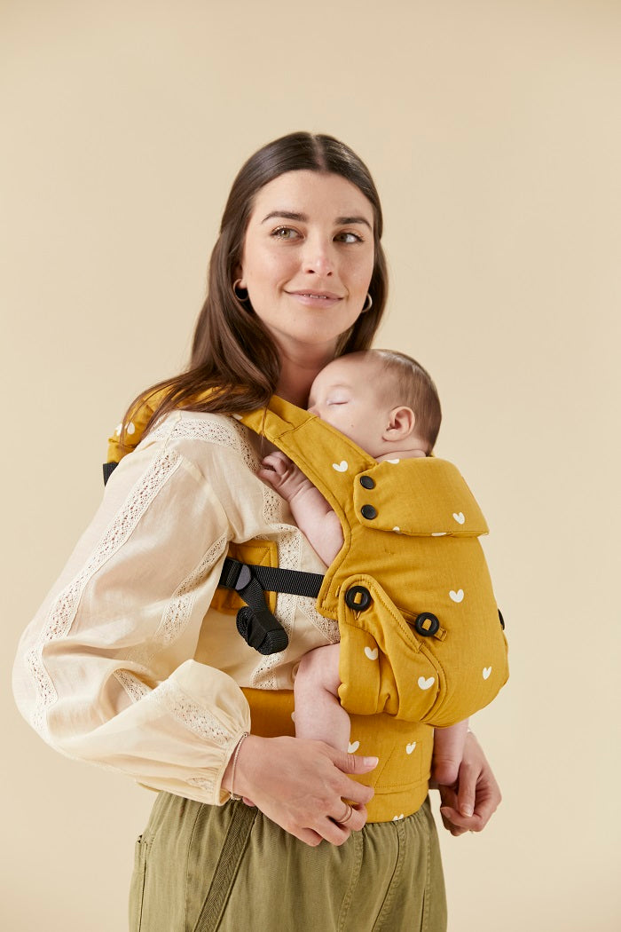 Mama nosi śpiące dziecko w ergonomicznej pozycji w nosidełku Tula Explore Play