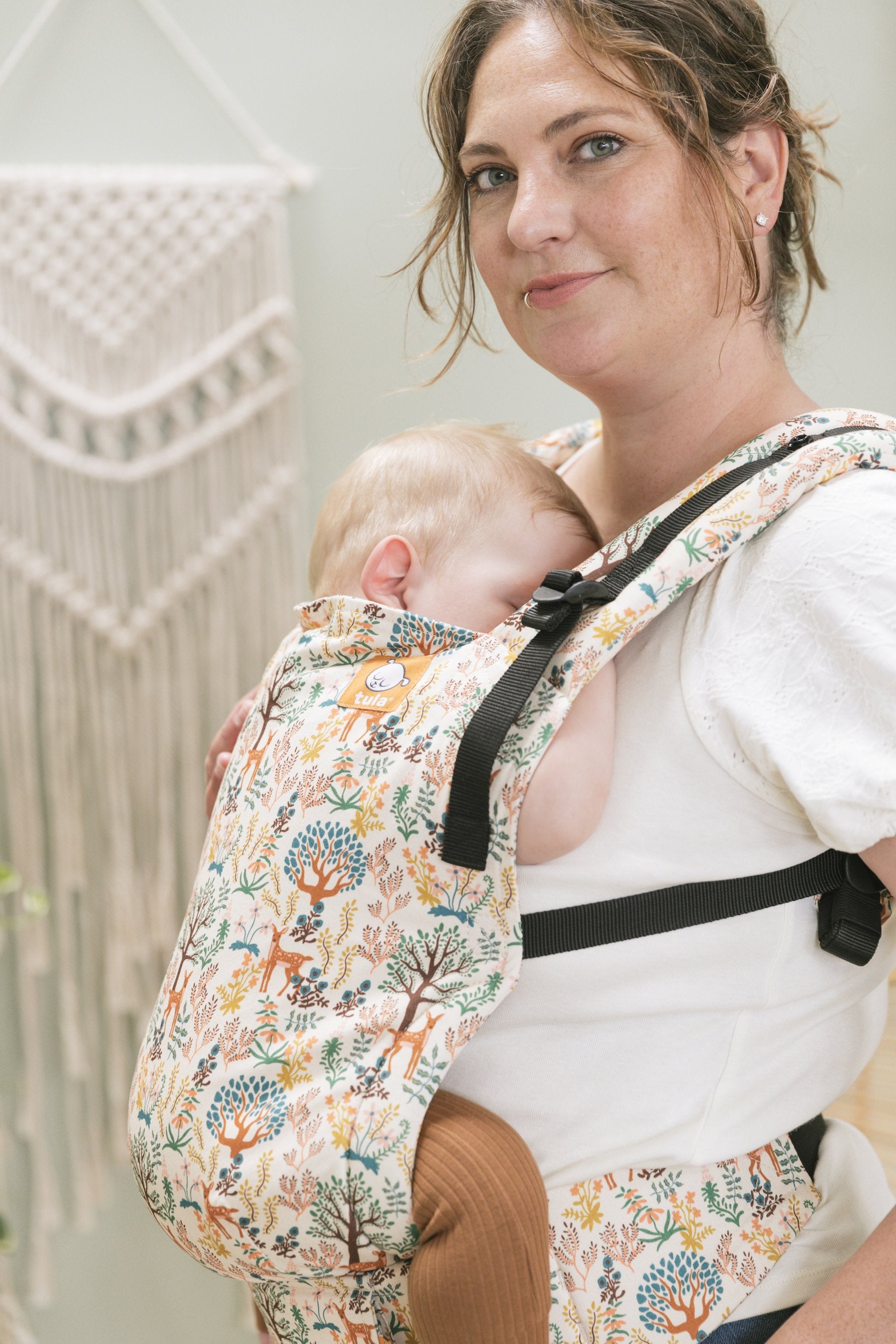 Mama nosi niemowlę w nosidełku Tula-Free-to-Grow Charmed w pozycji  przodem do rodzica.