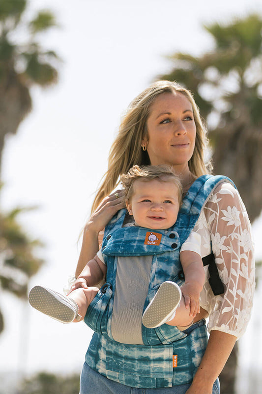Mama nosząca dziecko w ergonomicznym nosidełku Coast Shoal Explore w pozycji z przodu, przodem do rodzica