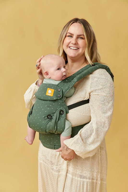 Mama nosi niemowlę w nosidełku Tula Explore Seedling w pozycji przodem do rodzica.