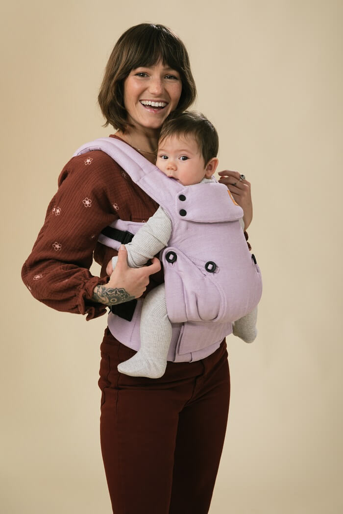 Uśmiechnięta mama nosi zaciekawione dziecko w nosidełku Tula Linen Explore z lnu i czesanej bawełny