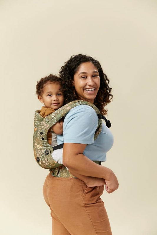 Mama nosi dziecko w nosidełku Explore Meadow w ergonomicznej pozycji na plecach