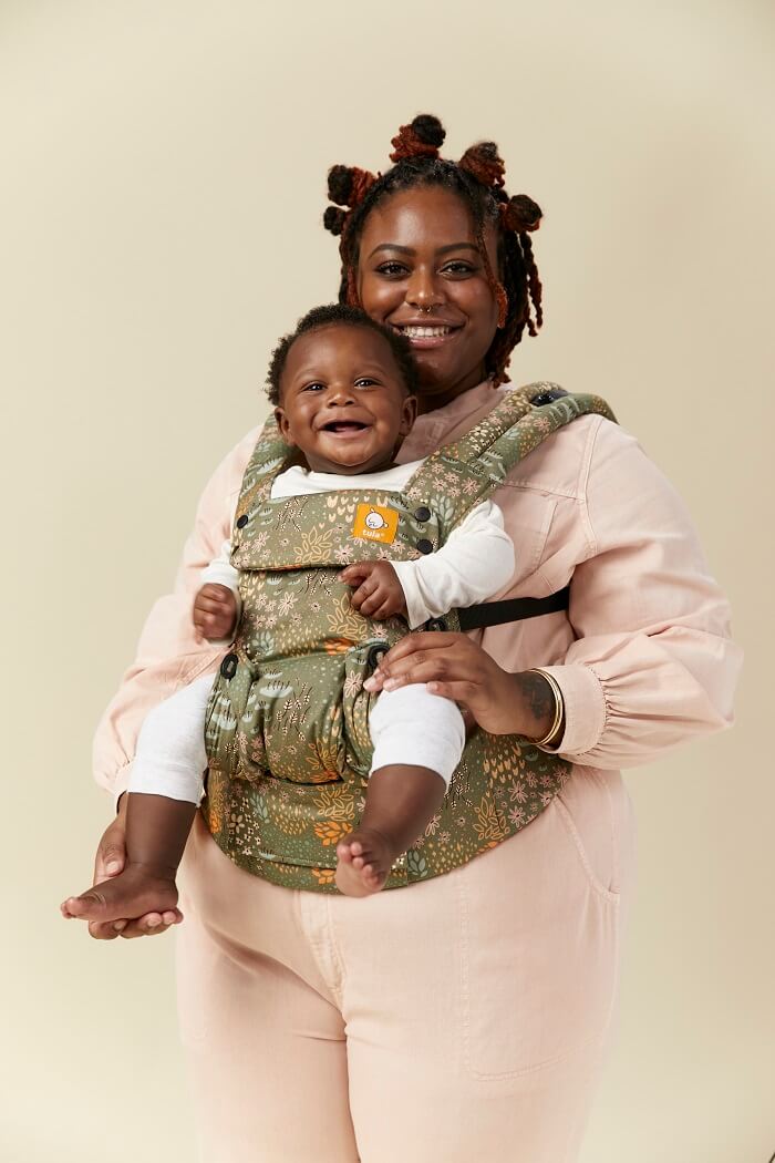 Uśmiechnięta mama nosi dziecko w nosidełku Tula Explore w pozycji przodem do świata