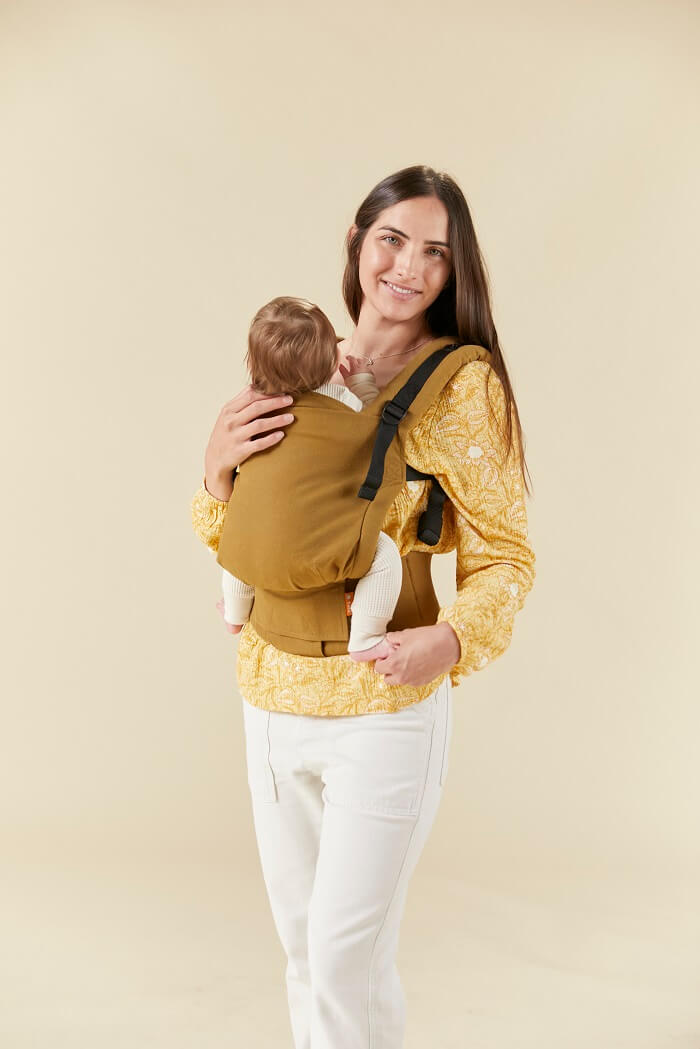 Mama nosi dziecko w nosidełku w ergonomicznej pozycji przodem do rodzica