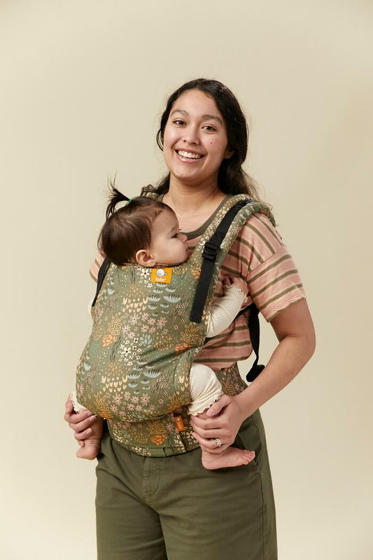 Mama nosi niemowlaka w nosidełku Tula Free-to-Grow Meadow w pozycji przodem do rodzica