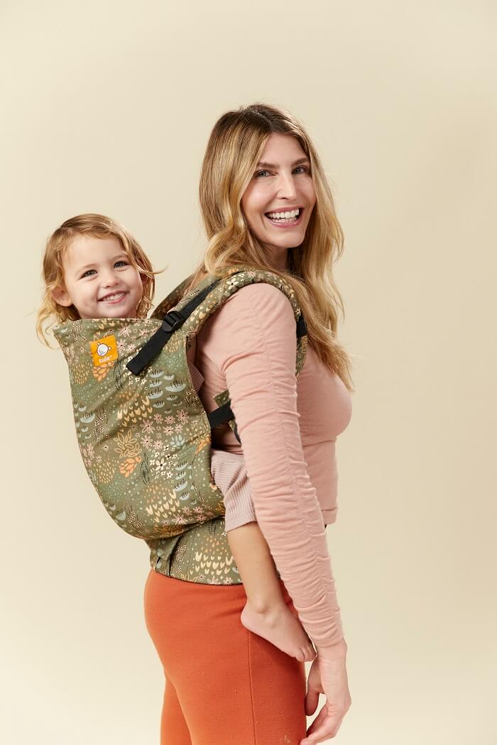 Mama nosi córeczkę w wygodnej pozycji na plecach w nosidełku Tula Toddler Meadow