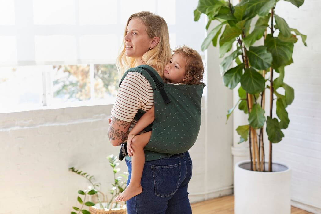 Dziecko w wieku przedszkolnym siedzi w nosidełku Tula Toddler Seedling w wygodnej pozycji na plecach mamy