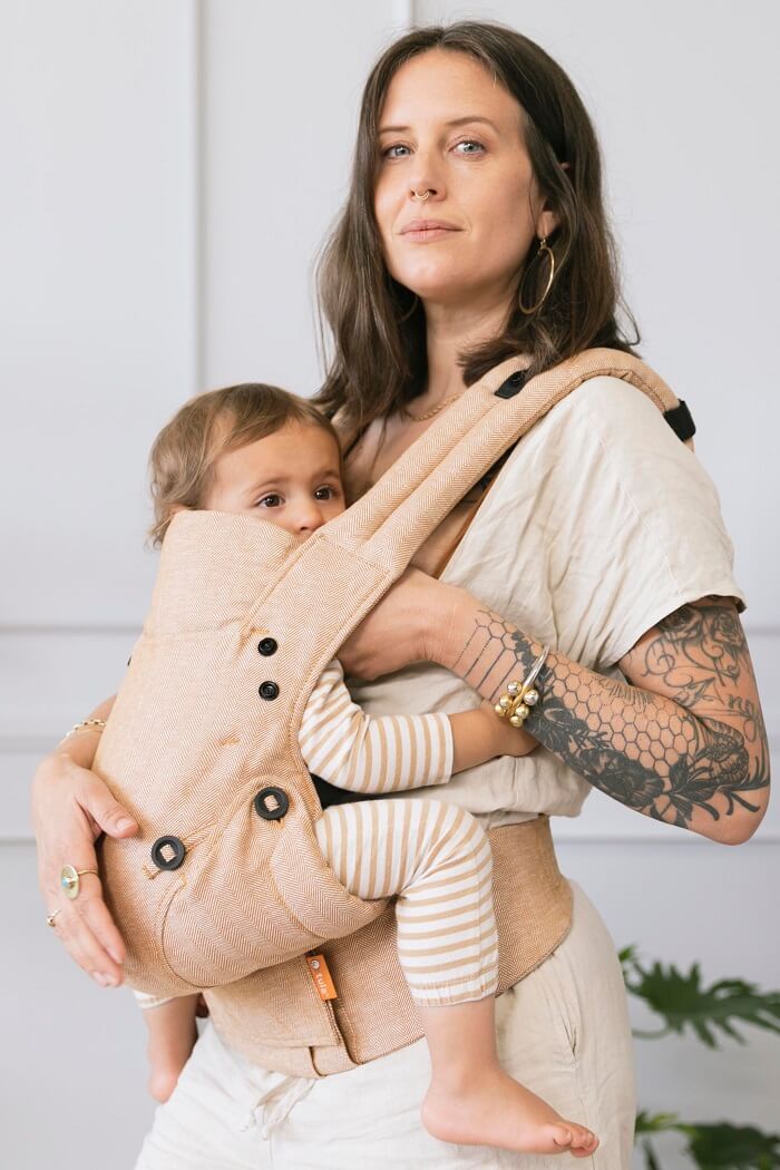 Mama karmi piersią niemowlę w nosidełku Tula Explore Linen Mesa.