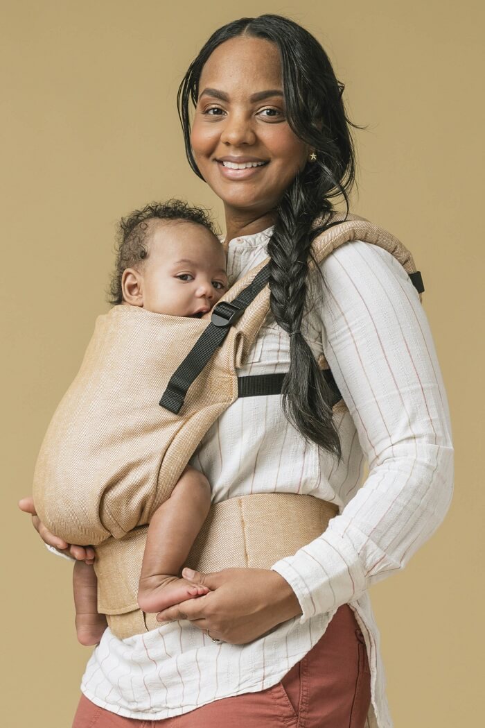 Uśmiechnięta mama z dzieckiem w nosidełku Tula Linen Free-to-Grow Mesa w ergonomicznej pozycji przodem do rodzica